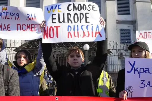 Protesters hold posters in front of the Russian Embassy in Kyiv, Ukraine, Tuesday, Feb. 22, 2022. Russia says that its recognition of independence for areas in eastern Ukraine extends to territory currently held by Ukrainian forces. That announcement Tuesday further raises the stakes amid Western fears that a full-fledged invasion of Ukraine is imminent. (AP Photo/Efrem Lukatsky)