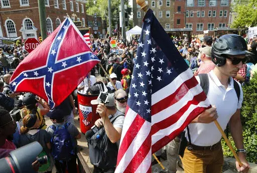 White nationalist demonstrators walk into Lee park surrounded by counter demonstrators in Charlottesville, Va., Saturday, Aug. 12, 2017.   In its annual report, released Wednesday, March 9, 2022, the Southern Poverty Law Center said it identified 733 active hate groups in 2021, down from the 838 counted in 2020 and the 940 counted in 2019. Hate groups had risen to a historic high of 1,021 in 2018, said the law center, which tracks racism, xenophobia and far right militias.(AP Photo/Steve Helber,