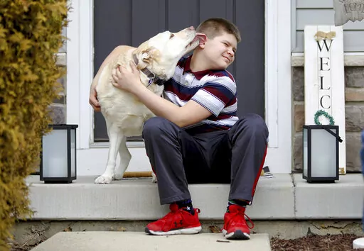 Nolan Balcitis, 12, sits with his dog, Callie, in front of his family's home in Crown Point, Ind., on March 4, 2022. Nolan was diagnosed with Type 1 diabetes six months after a mild case of COVID-19. Reports of rising diabetes cases during the pandemic have scientists exploring if there could be a link with the coronavirus. Emerging evidence shows the virus can attack insulin-producing cells in the pancreas, a process that might trigger diabetes in susceptible people. (AP Photo/Teresa Crawford)