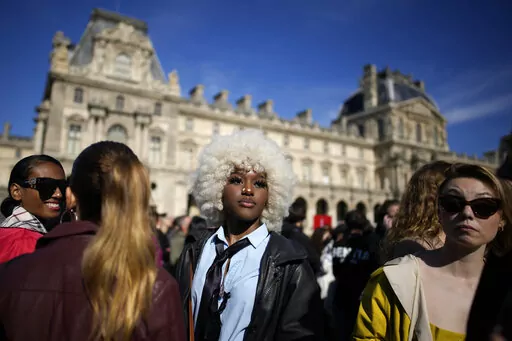 Fashion lovers wait in the courtyard of the Louvre museum during Louis Vuitton ready-to-wear Spring/Summer 2023 fashion collection presented Tuesday, Oct. 4, 2022 in Paris. (AP Photo/Christophe Ena)
