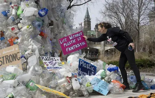 Activist Dianne Peterson places a sign on an art installation outside a United Nations conference on plastics, April 23, 2024, in Ottawa, Ontario. (Adrian Wyld/The Canadian Press via AP. File)