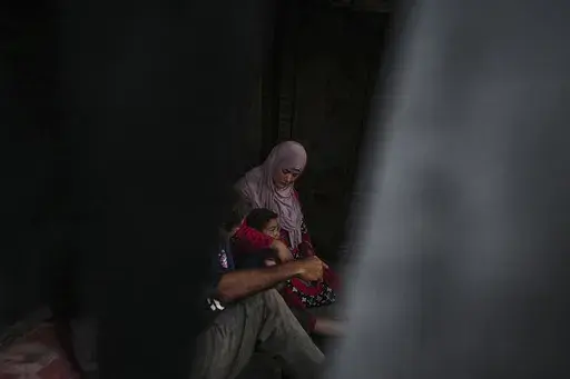 Basima al-Batsh sits with her family ahead of the Eid al-Adha holiday in Deir al Balah, Gaza Strip, Tuesday, June 11, 2024. They were displaced from their home by the war between Israel and Hamas. (AP Photo/Abdel Kareem Hana)