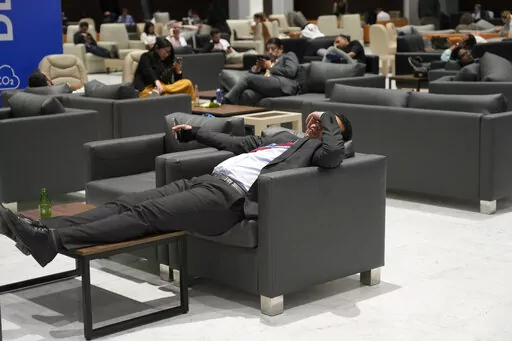 Attendees and members of the media lounge as they wait for a closing plenary session at the COP27 U.N. Climate Summit, Sunday, Nov. 20, 2022, in Sharm el-Sheikh, Egypt. (AP Photo/Peter Dejong)