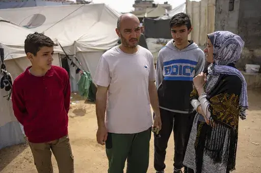Heba al-Haddad, right, and her family displaced from Gaza City, stand in a makeshift tent camp in Rafah, southern Gaza, Friday, March 29, 2024. Al-Haddad was forced out of her home in Gaza City on March 21 when Israeli troops stormed her apartment and ordered her and her family to leave for the south. Amid fighting that has engulfed the area since Israel raided Shifa Hospital, witnesses say troops have been pushing residents out of nearby neighbourhoods. (AP Photo/Fatima Shbair)