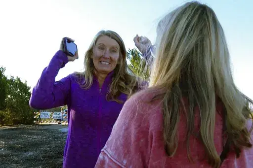 Mary Lord of Ft. Worth, Texas, mother of groom Eric Lord raises her hands hearing the news that some of the bridesmaids’ dresses, tuxedoes are being brought as A.J. McCullough of Sunset Beach, NC, mother of bride Monroe McCullough stands by on Saturday, Oct. 1, 2022 in Pawleys Island, S.C. The perfect wedding day almost didn't come together for two families who traveled to the island for nuptial festivities that almost got derailed by Hurricane Ian's landfall and aftermath.(AP Photo/Allen Bree