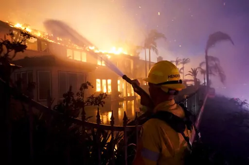 A firefighter works to put at a structure burning during a wildfire Wednesday, May 11, 2022, in Laguna Niguel, Calif. (AP Photo/Marcio J. Sanchez)
