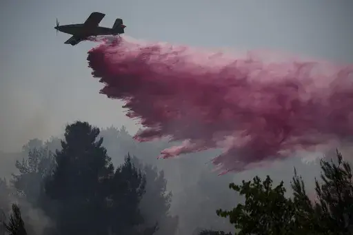 A plane uses a fire retardant to extinguish a fire burning in an area near the border with Lebanon, in Safed, northern Israel, Wednesday, June 12, 2024. Scores of rockets were fired from Lebanon toward northern Israel on Wednesday morning, hours after Israeli airstrikes killed four officials from the militant Hezbollah group including a senior military commander. (AP Photo/Leo Correa, File)