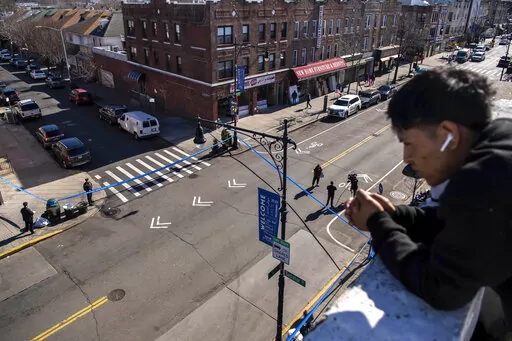 FILE —-Erafin Yaz, 25, looks from his roof at the caution tape covering the corner of Bay Ridge Avenue and 5th Avenue where pedestrians were struck Monday, Feb. 13, 2023, in the Brooklyn borough of New York. Delivery worker YiJie Ye was struck and killed by a U-Haul truck during a miles-long rampage, that barreled into bicyclists, moped riders, a police car and one pedestrian. (AP Photo/Brittainy Newman)